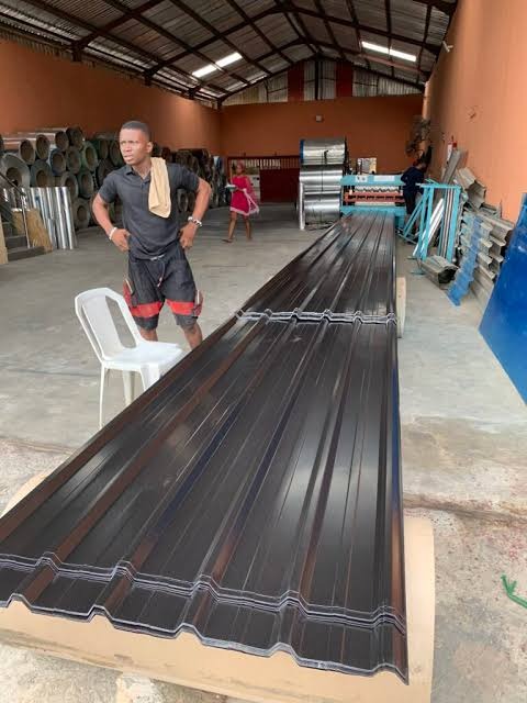 Red metal roofing sheets coming off the roll-forming line